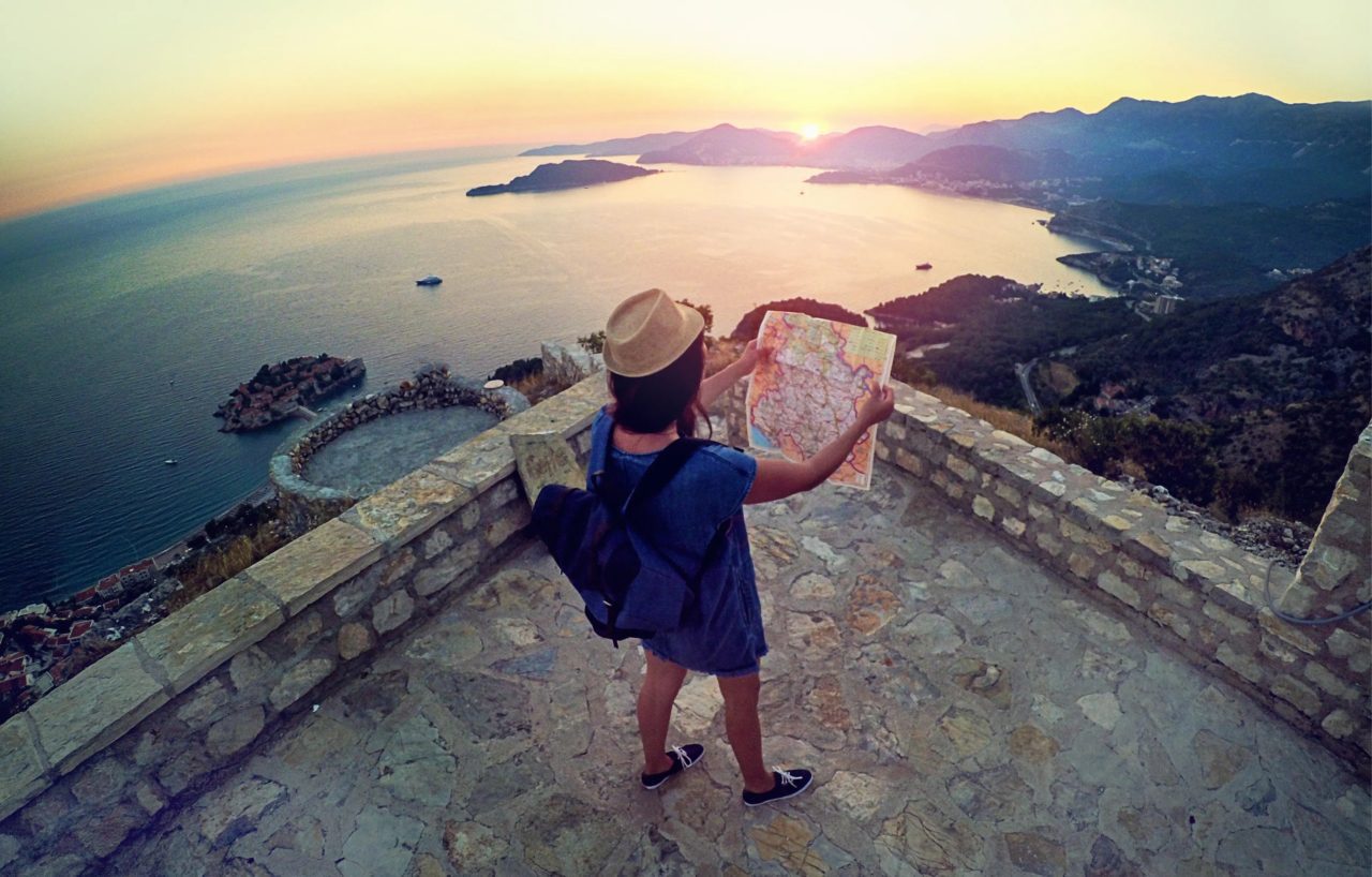 Woman looking at map with sunset in front of her.
