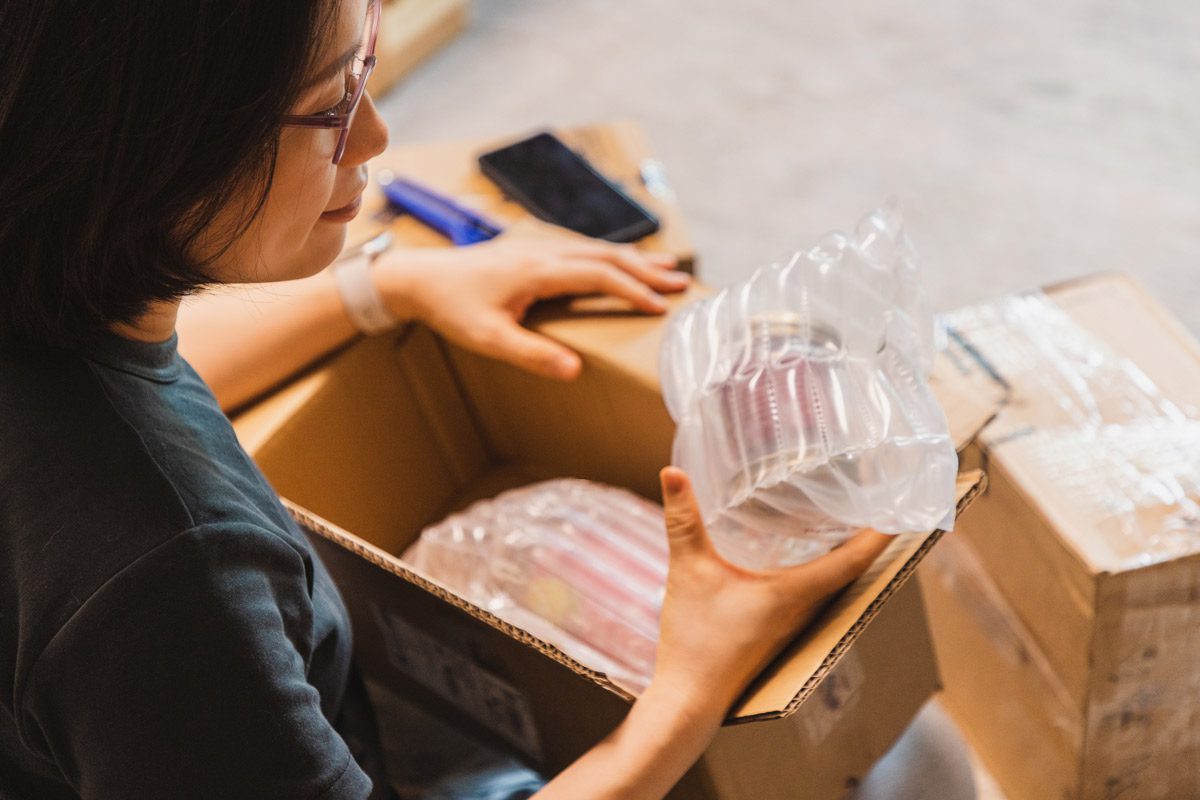 Woman opening box with shipping pillows.