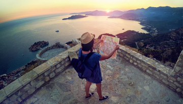 Woman looking at map with sunset in front of her.